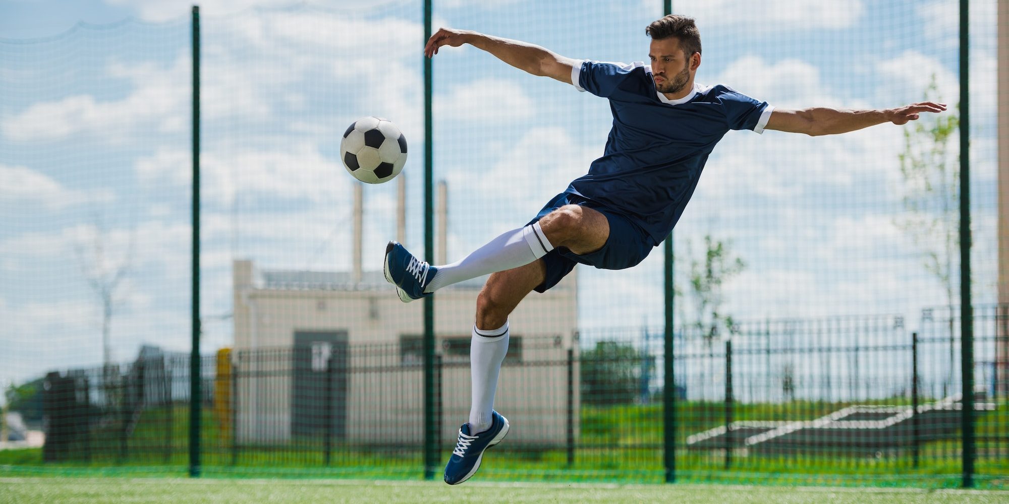 athletic soccer player kicking ball on soccer pitch